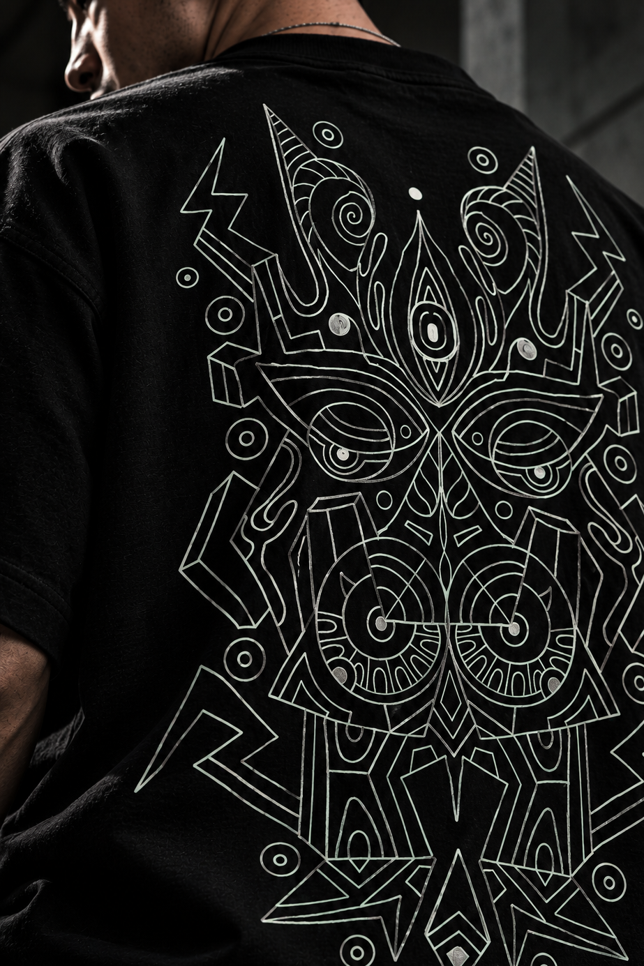 A person wearing a black LMNO T-shirt, shown from the back, featuring a large white geometric line-art graphic.