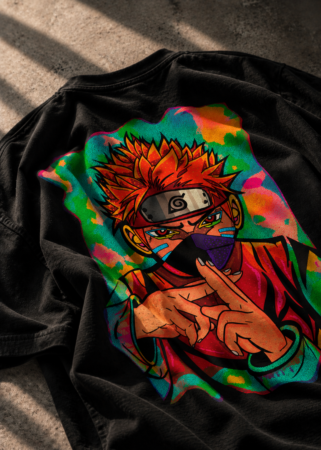 A black LMNO T-shirt laid flat on a textured concrete surface, featuring a large colorful anime-style graphic print.