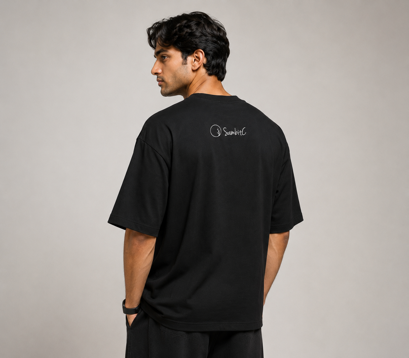 Male Model wearing a black t-shirt with a logo on the back against a plain background
