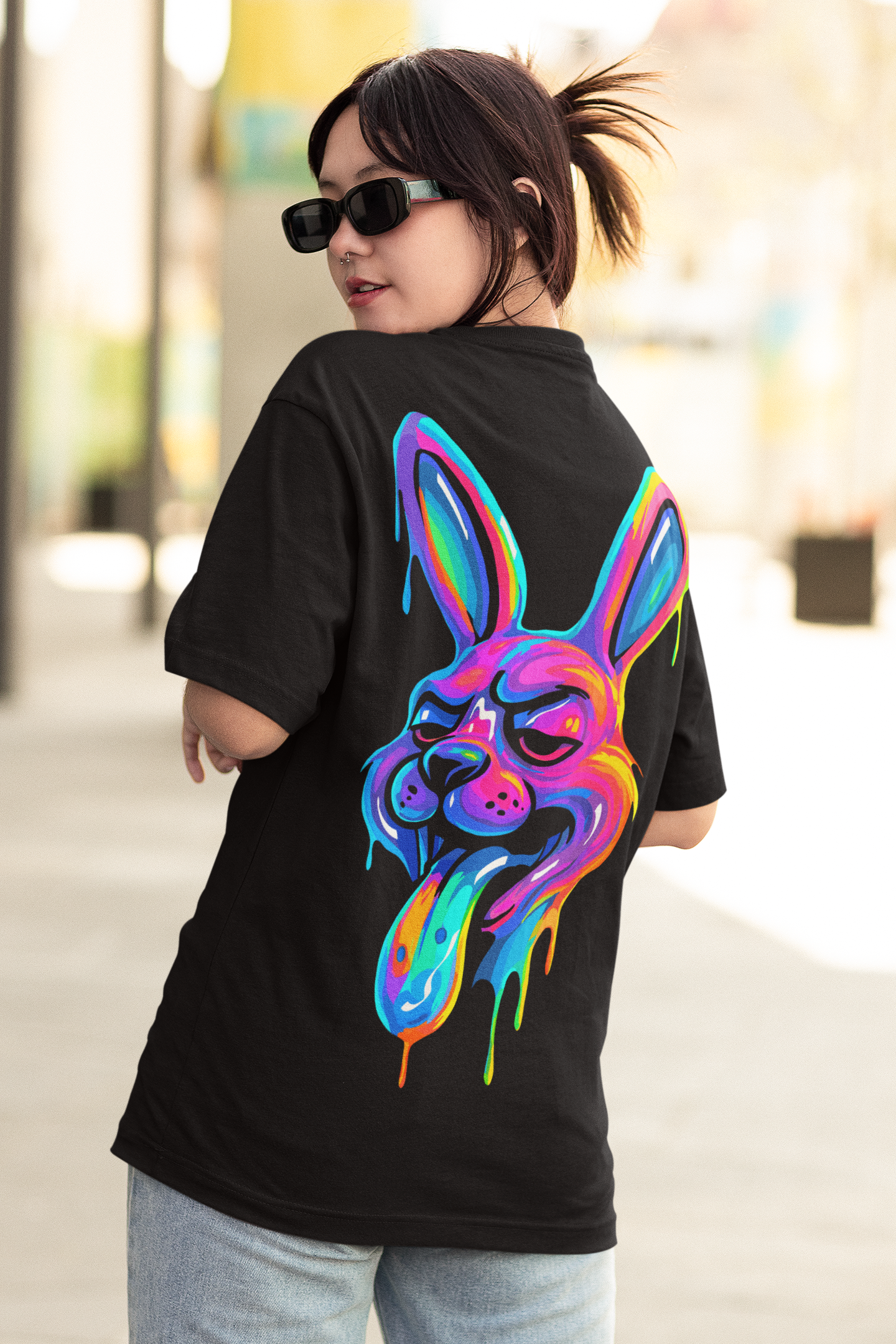 Model wearing JACKRABBIT psychedelic rabbit oversized t-shirt by LMNO streetwear, wearing sunglasses and looking back